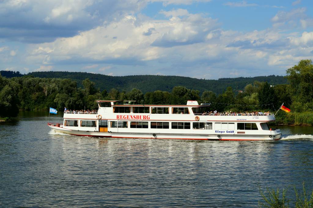 Das Bild zeigt ein Schiff unter deutscher Flagge, auf dem Regensburg steht.